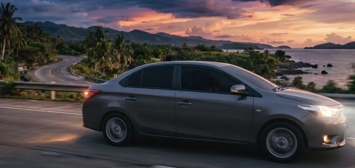Self-drive sedan on a coastal road in Cebu at sunset
